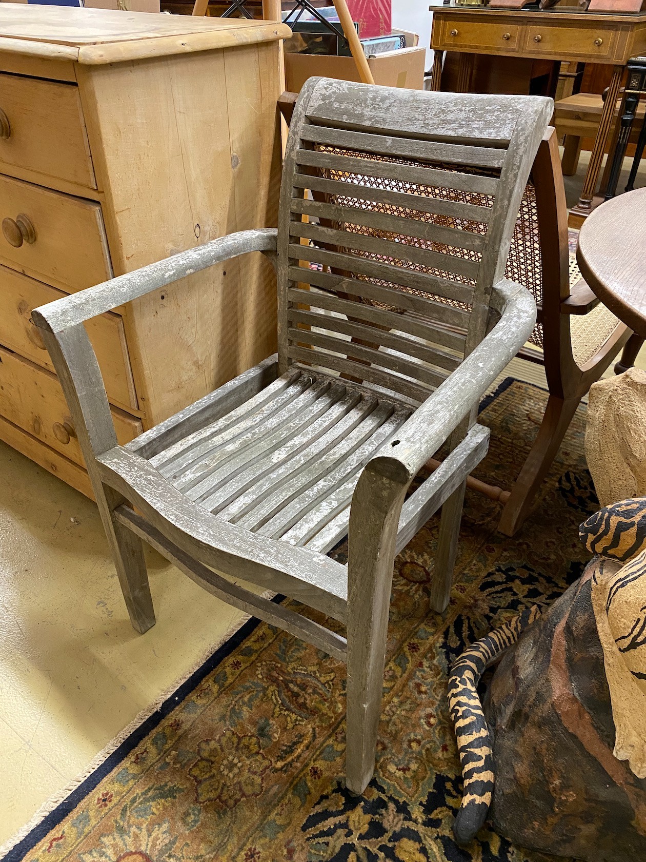 A pair of weathered teak slatted garden elbow chairs, width 65cm, depth 45cm, height 95cm